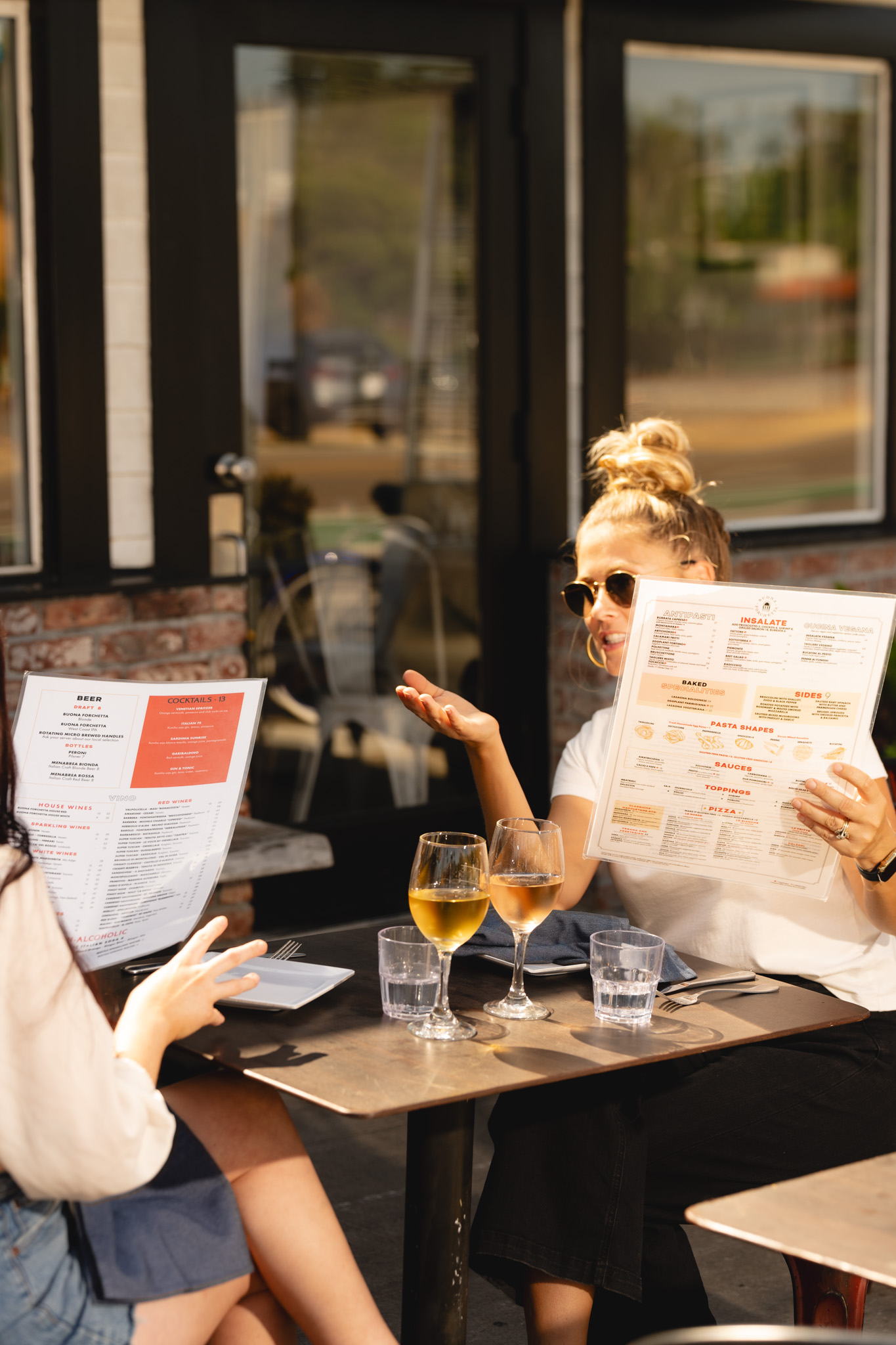 Ladies chatting at a table outdoors while holding menus